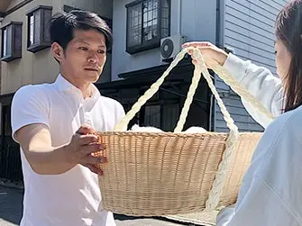 ペット火葬ハピネスのスタッフが自宅前でペット用のかごを運ぶ様子